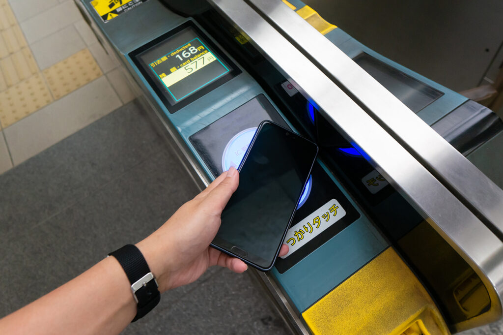Using a smartphone to enter a station in Japan at an automatic ticket gate.